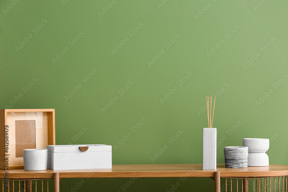 Bottle of reed diffuser and decor on table near color wall in room