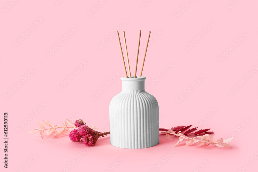 Floral reed diffuser and flowers on pink background