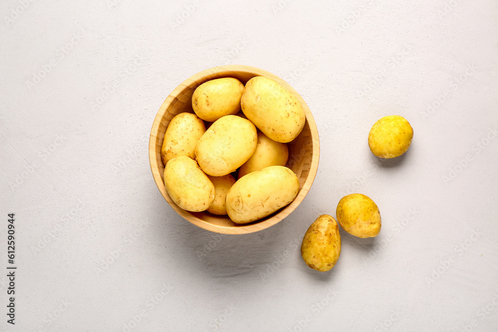 Wooden bowl with raw baby potatoes on grey background