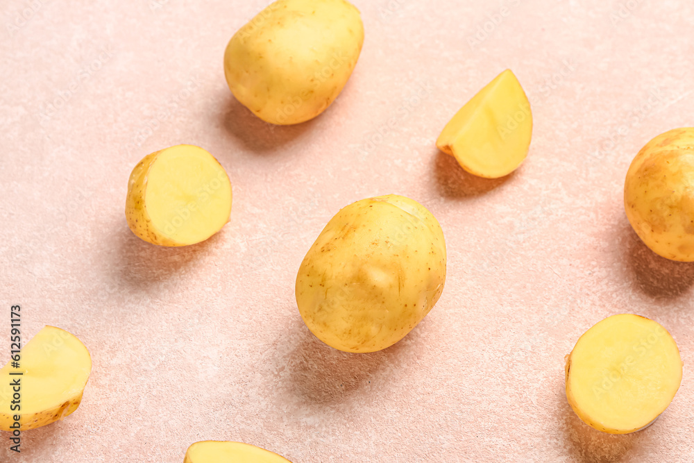 Raw baby potatoes and slices on pink background