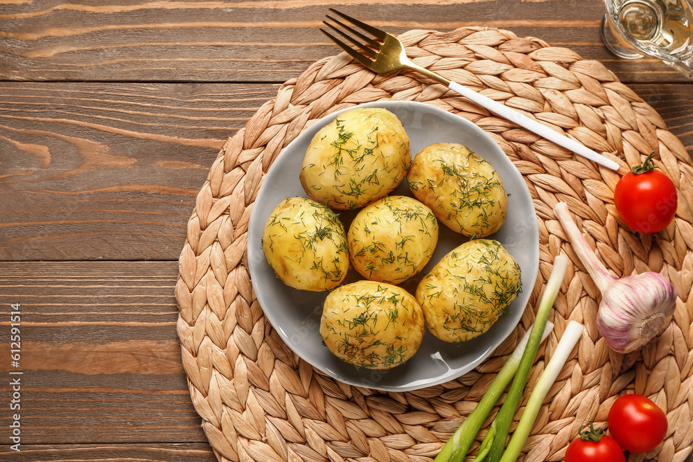 Plate of boiled baby potatoes with dill and green onion on wooden background