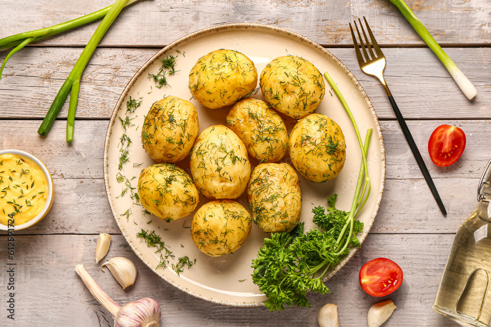 Plate of boiled baby potatoes with dill and tomatoes on grey wooden background