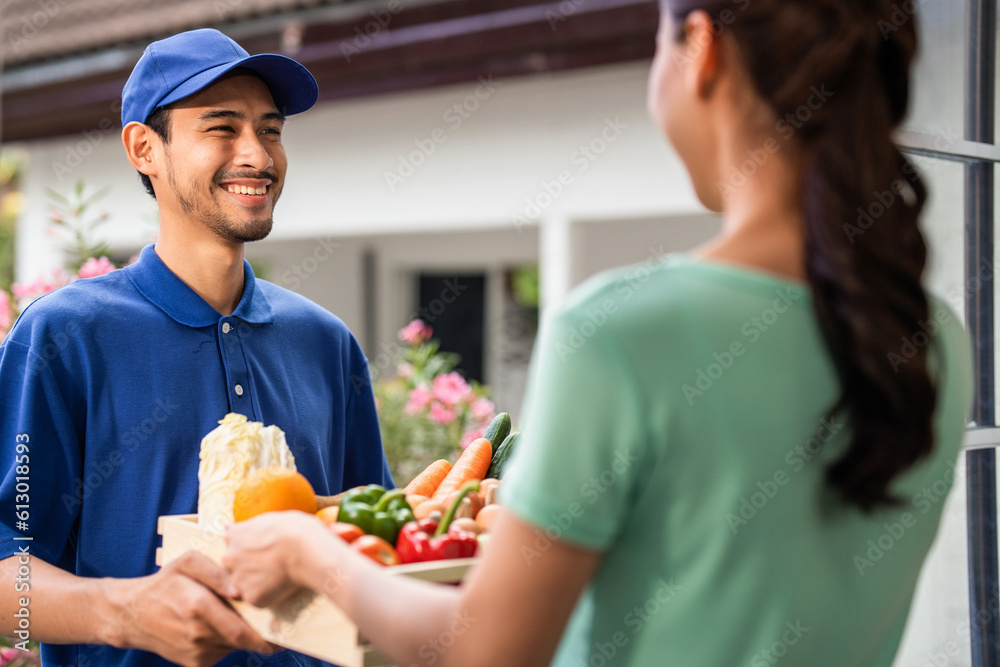 Asian young delivery man delivering package to female customer at home. 