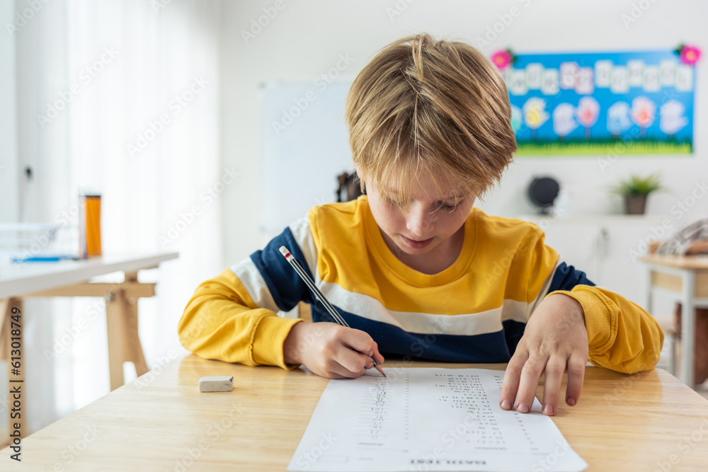 Caucasian young boy student doing an exam test at elementary school.