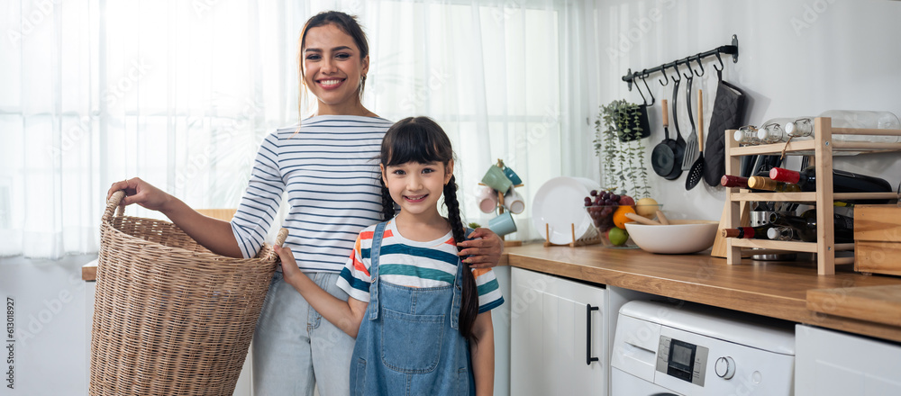 Portrait of Caucasian mother and daughter look at camera in kitchen. 