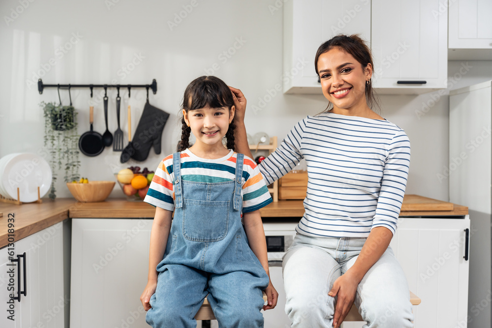 Portrait of Caucasian mother and daughter look at camera in kitchen. 