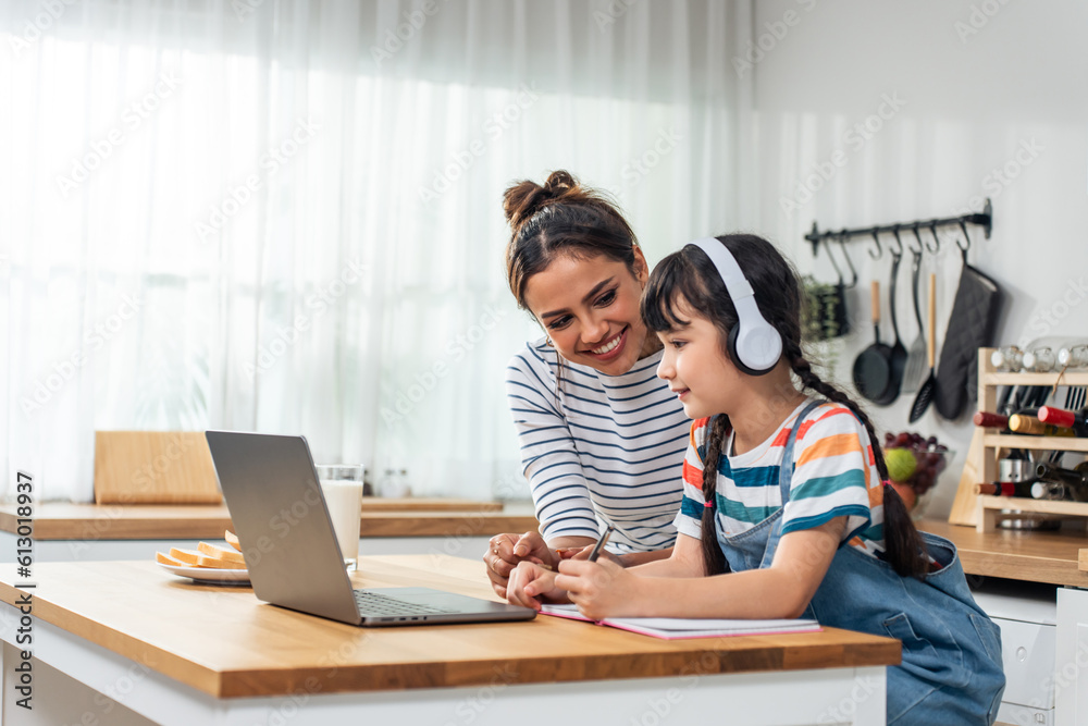 Caucasian young girl kid learning online class at home with mother. 