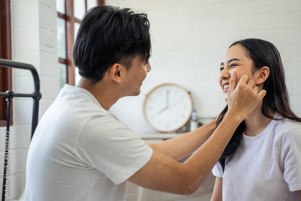 Asian new marriage couple sitting on bed and looking at each other.