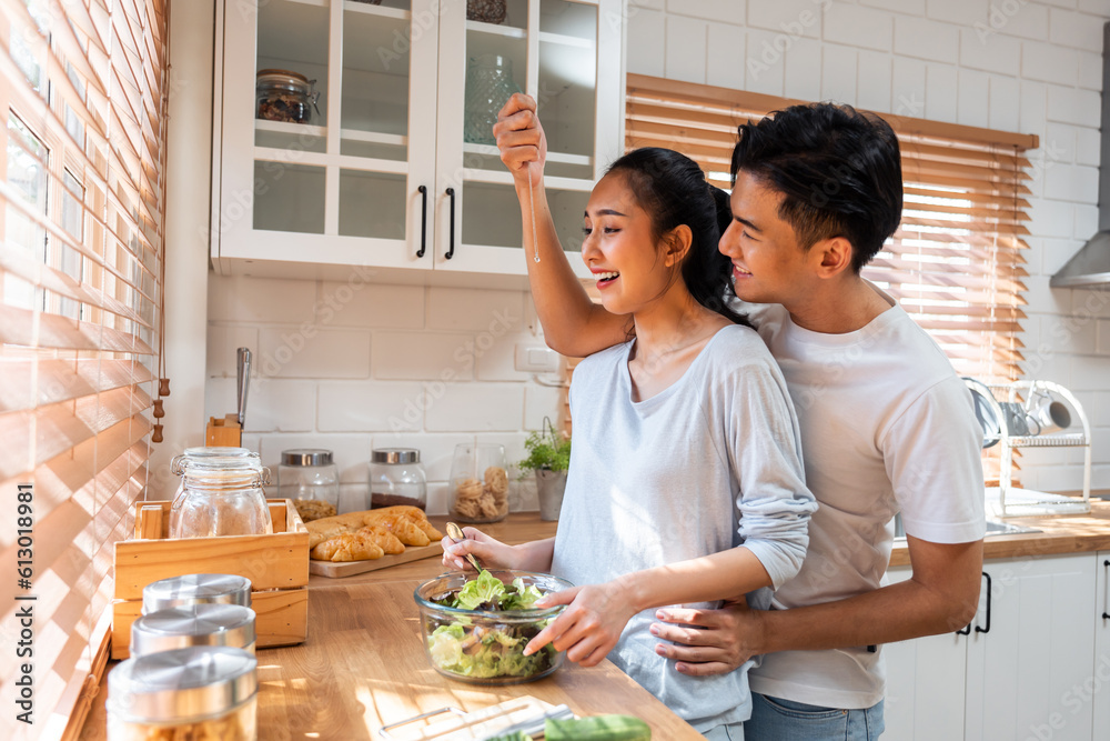 Asian romantic man making surprise girlfriend with necklace in kitchen. 