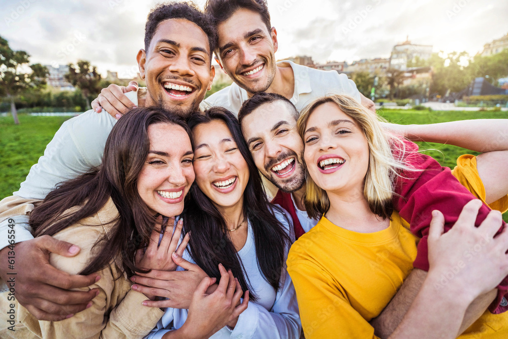 Multicultural young people smiling at camera outdoors - Happy friends having fun hanging out togethe