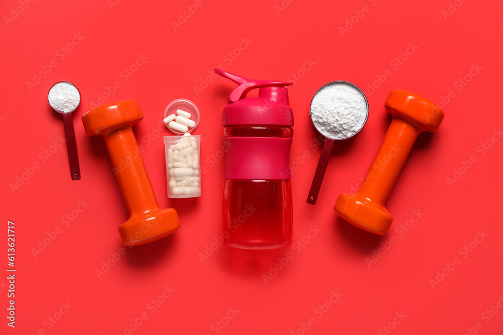 Composition with bottle of water, dumbbells, amino acid pills and powder on red background