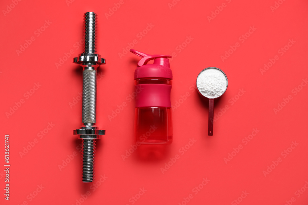 Bottle of water, scoop with amino acid supplement and dumbbell on red background