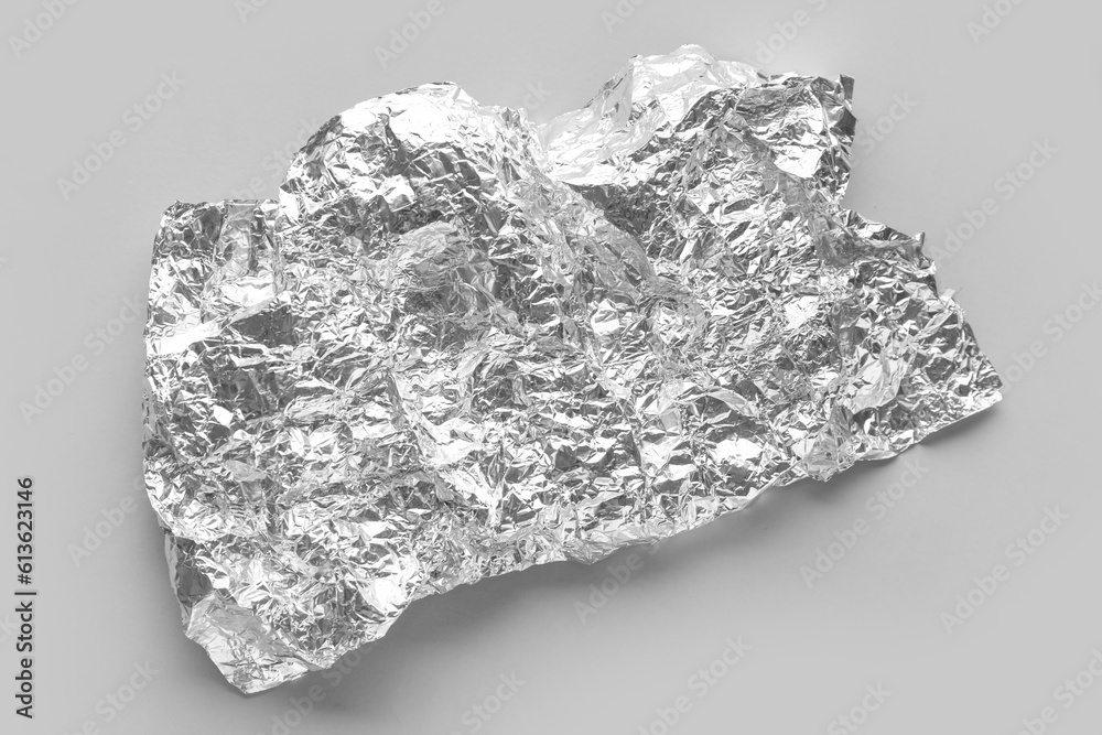 Crumpled sheet of aluminium foil on grey background