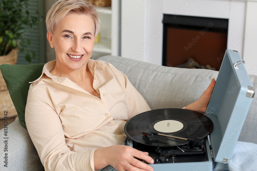 Mature woman with record player lying on sofa at home