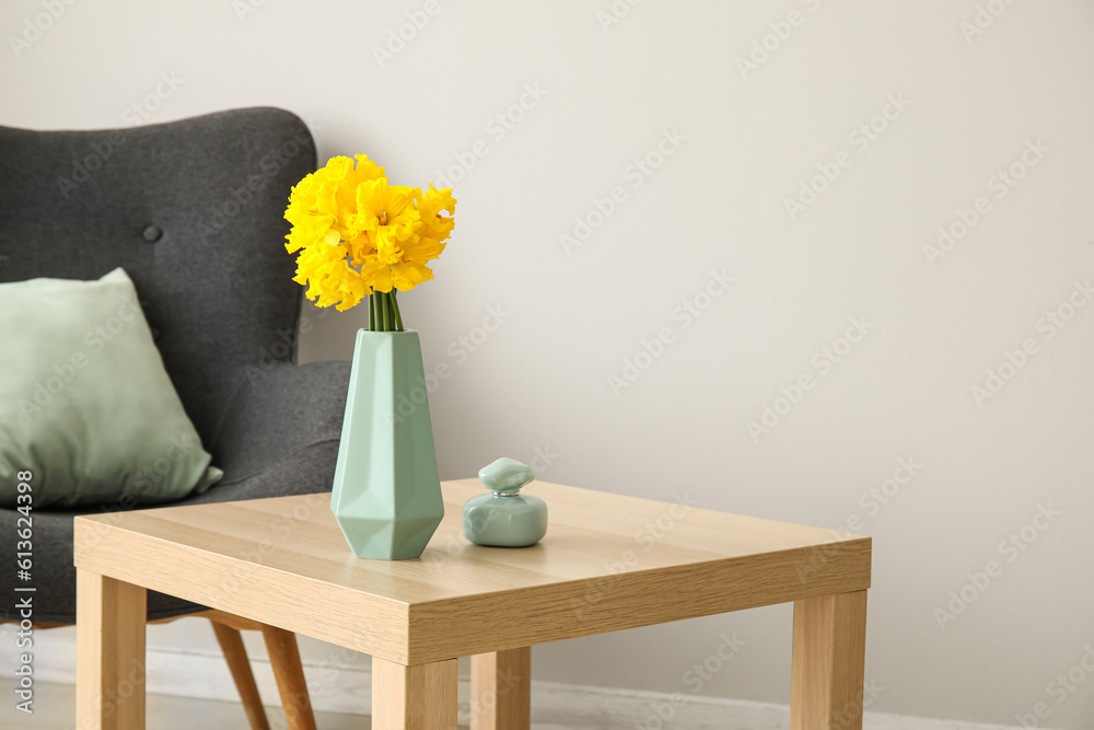 Vase with narcissus flowers and perfume on table in living room