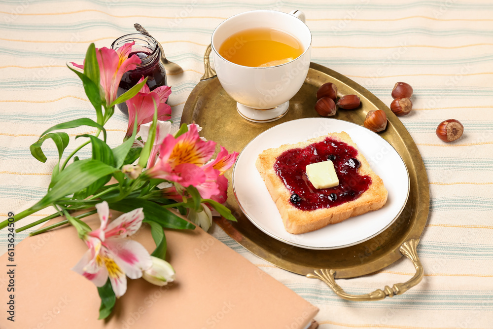 Tasty toast with jam, cup of tea and beautiful flowers on table