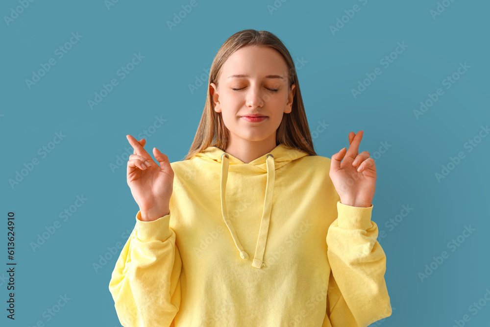 Teenage girl crossing fingers on blue background