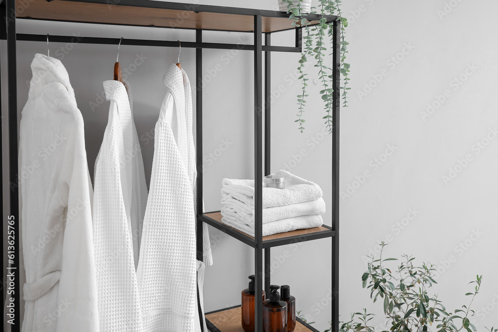 Shelving unit with bathrobes and clean towels in bathroom