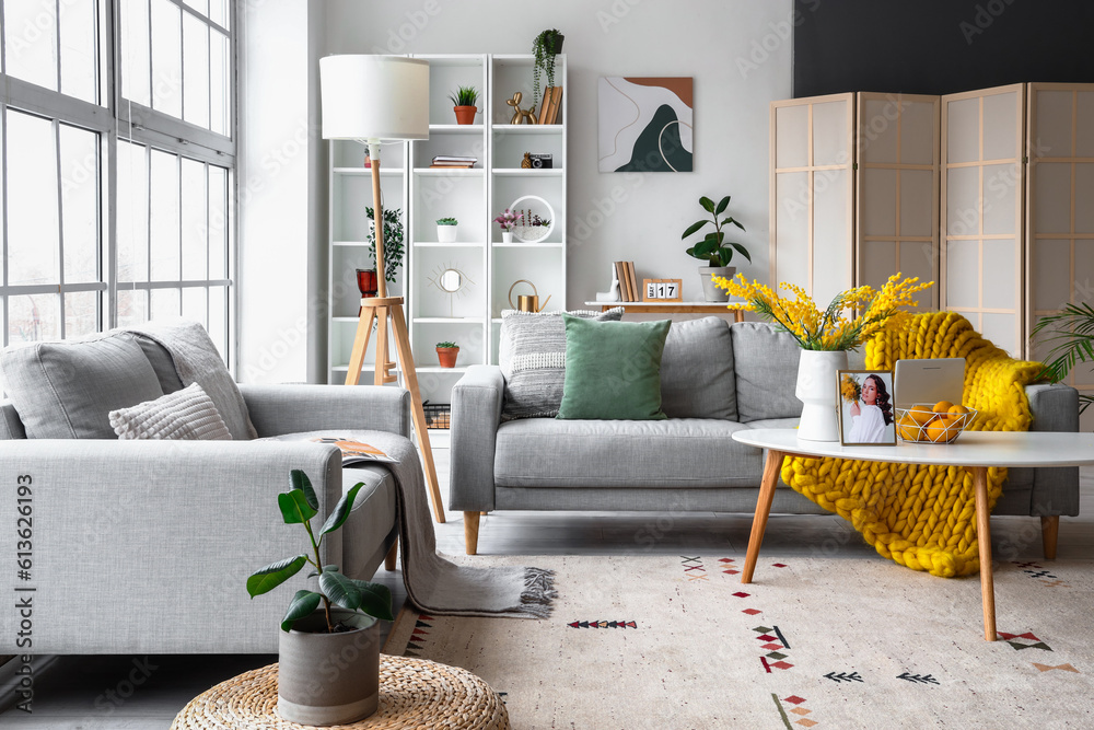 Interior of bright living room with cozy sofas near big window