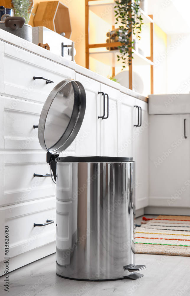 Opened metallic trash bin on floor in modern kitchen