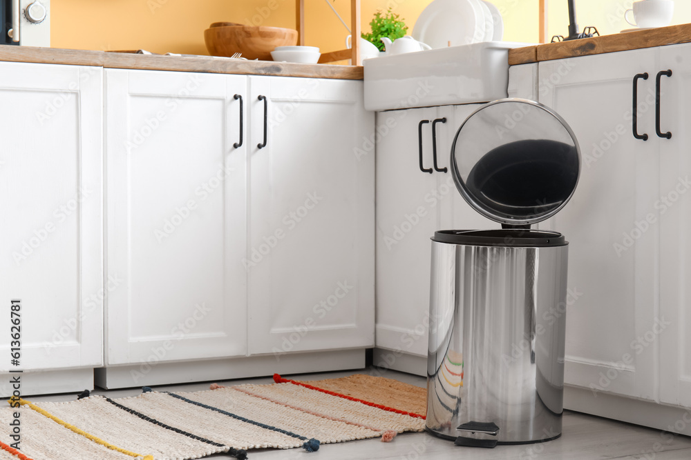 Opened metallic trash bin on floor in modern kitchen