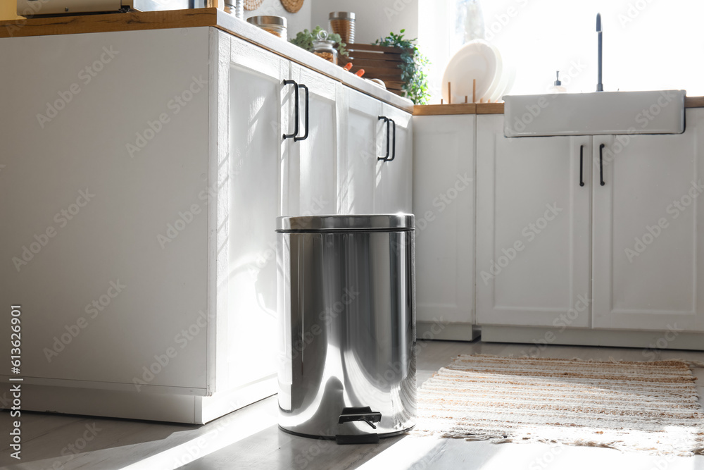 Metallic trash bin on floor in modern kitchen