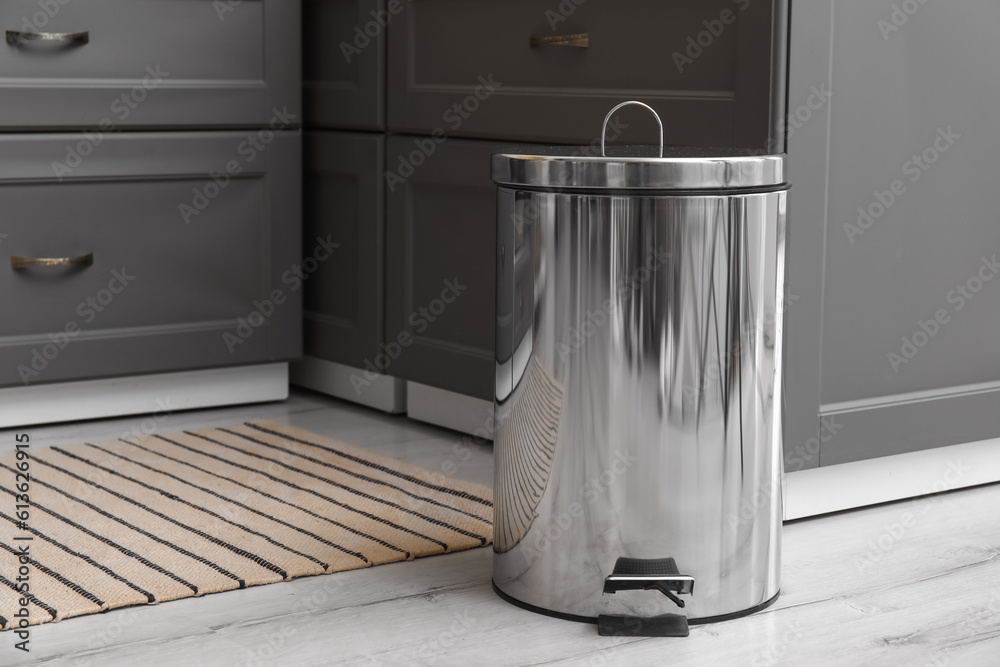 Metallic trash bin on floor in modern kitchen