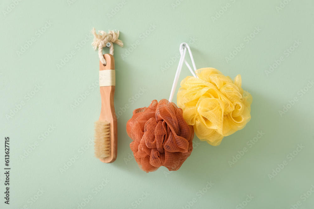 Bath loofahs with massage brush hanging on green wall