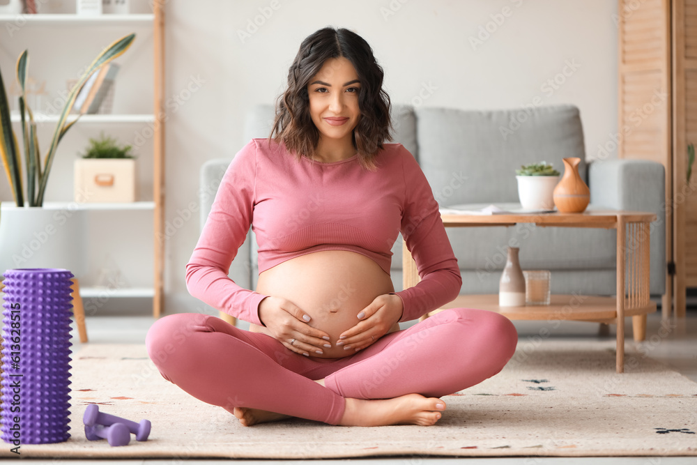 Sporty pregnant woman sitting at home