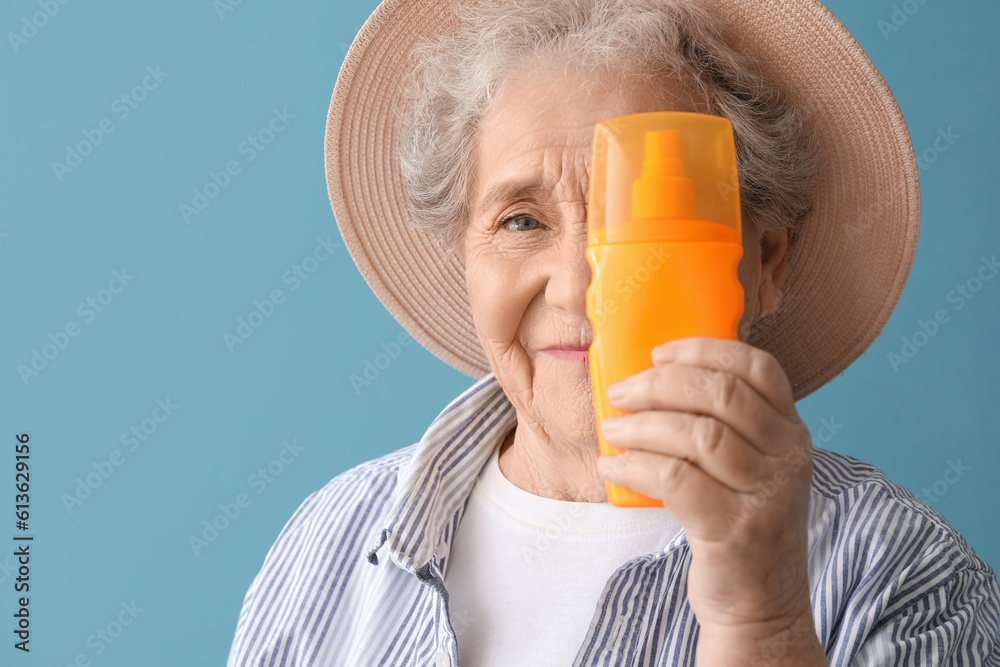 Senior woman with sunscreen cream on blue background, closeup