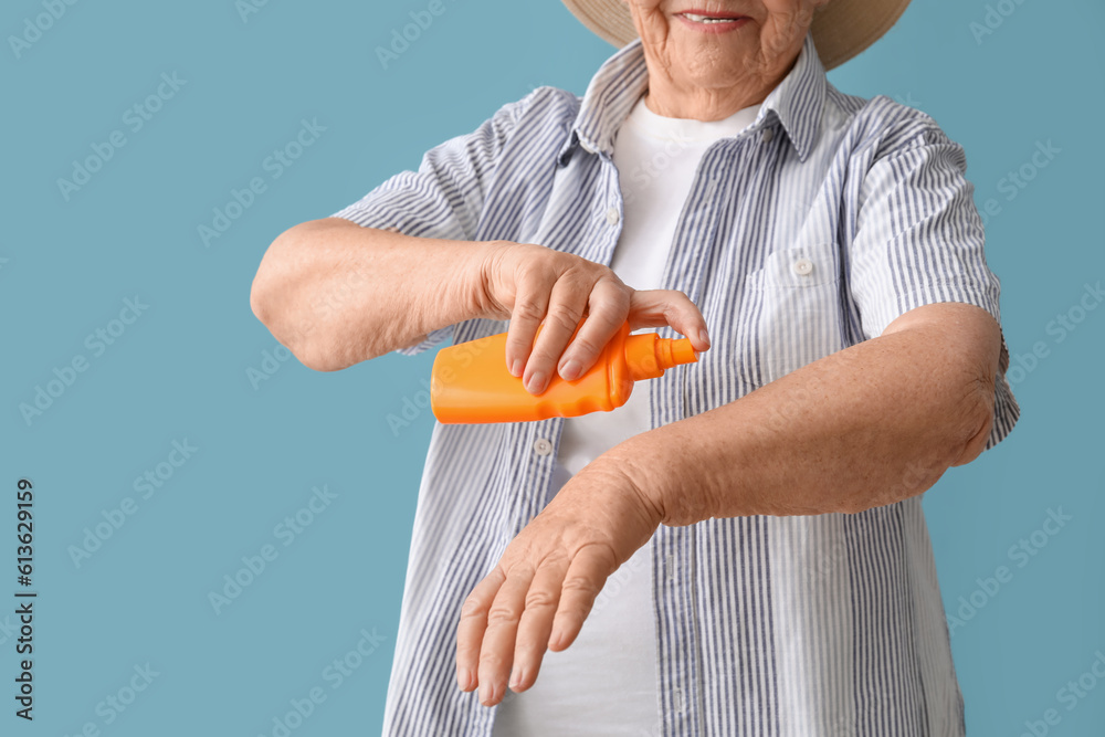 Senior woman with sunscreen cream on blue background, closeup