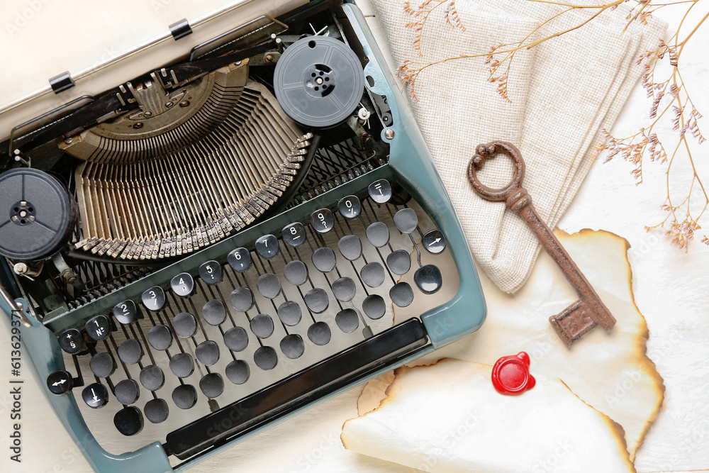 Composition with vintage typewriter, key, old parchment and blooming tree branch on white wooden tab