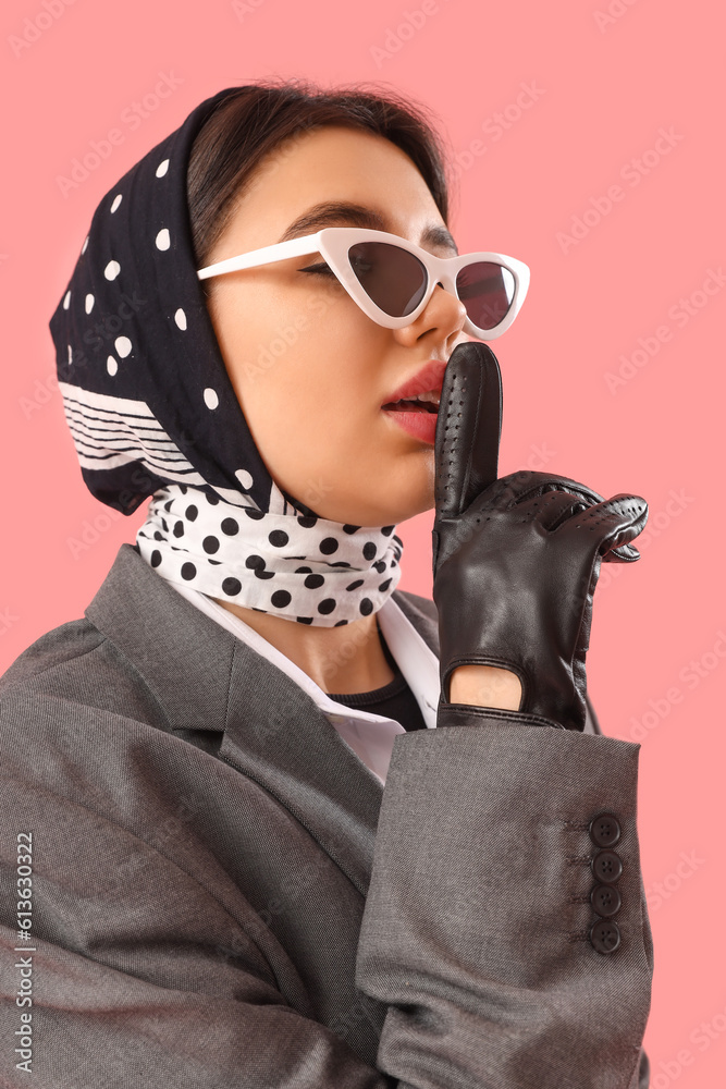 Stylish young woman in leather gloves showing silence gesture on pink background, closeup