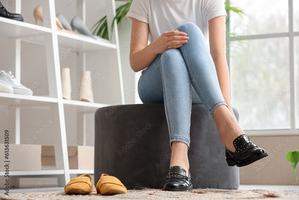 Woman trying on stylish black shoes in boutique