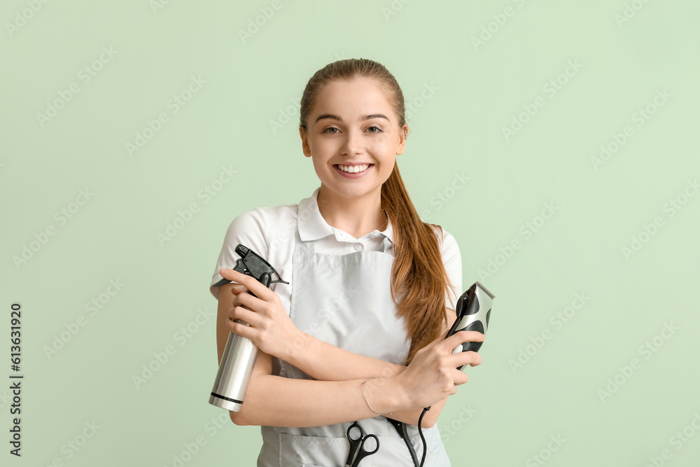 Female hairdresser with trimmer and spray on green background