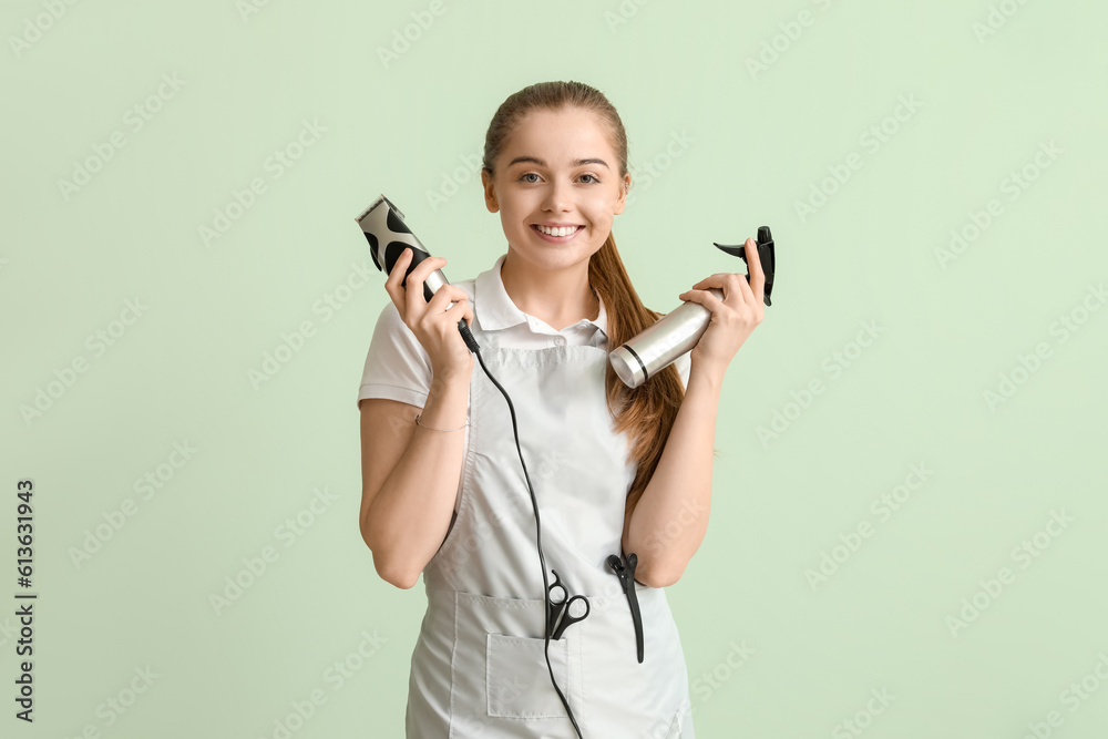 Female hairdresser with trimmer and spray on green background