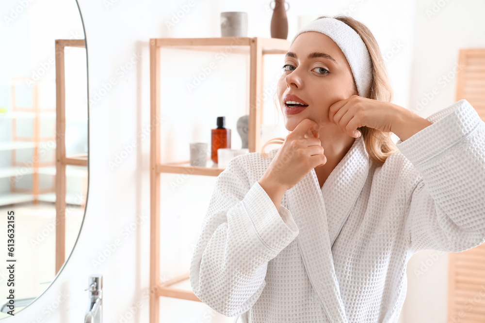 Young woman doing face building exercise in bathroom