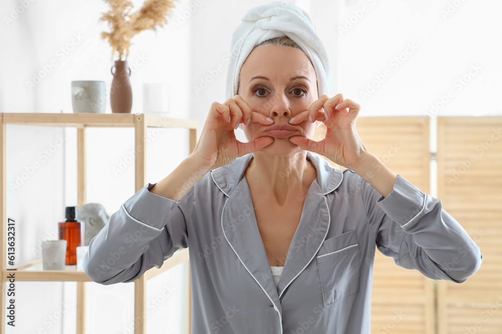 Mature woman doing face building exercise in bathroom