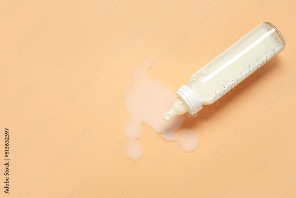 Bottle of milk for baby on pale orange background