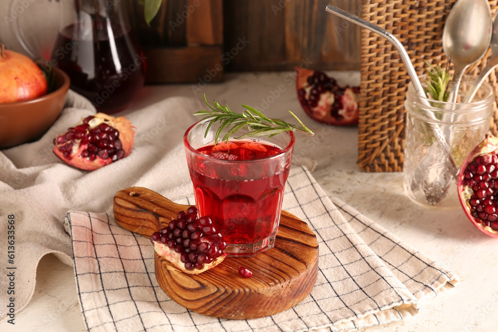 Bowl with fresh pomegranate and glass of juice on white table