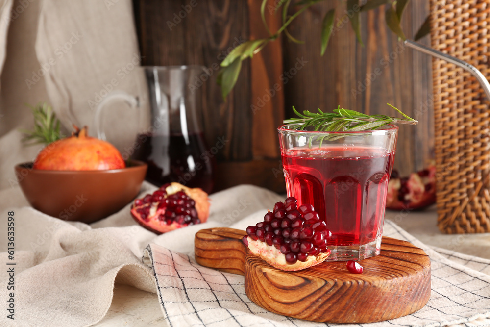 Bowl with fresh pomegranate and glass of juice on white table