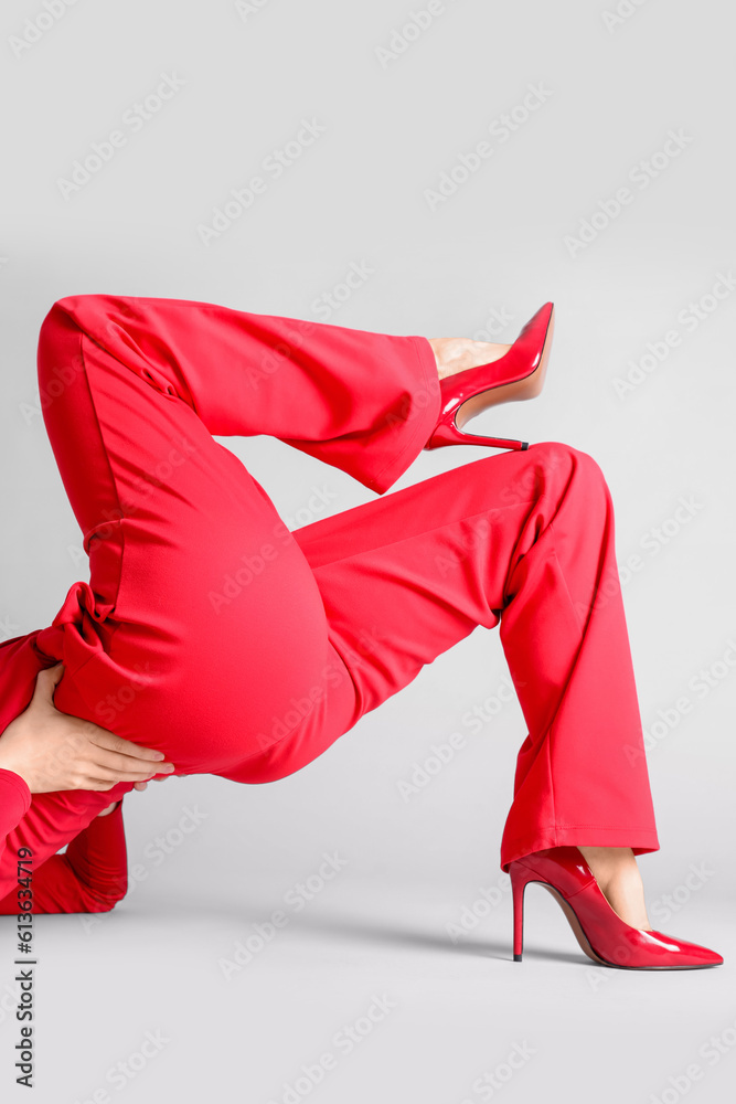 Female legs in red high heels on grey background