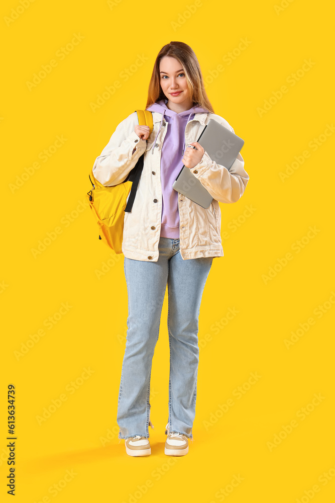 Female student with laptop on yellow background