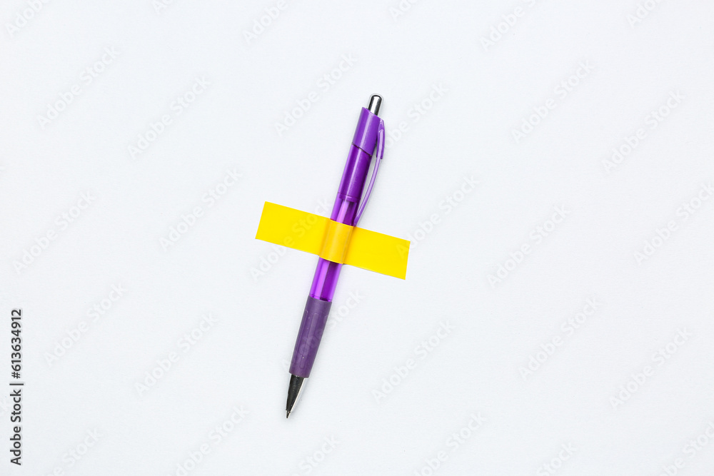 Pen with adhesive tape on light background