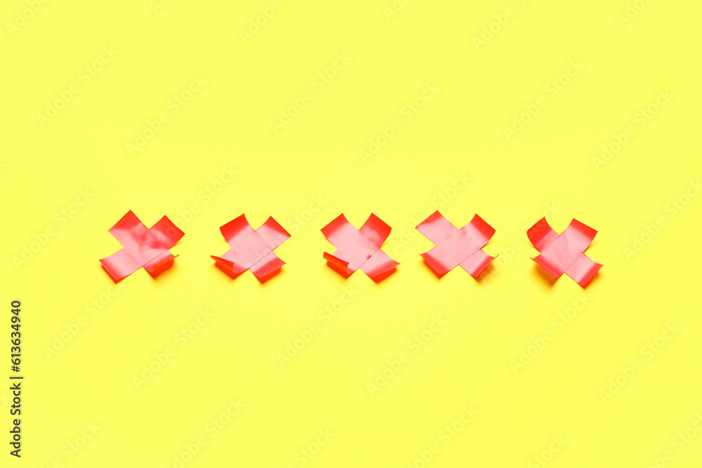 Red crosses made of adhesive tape on yellow background