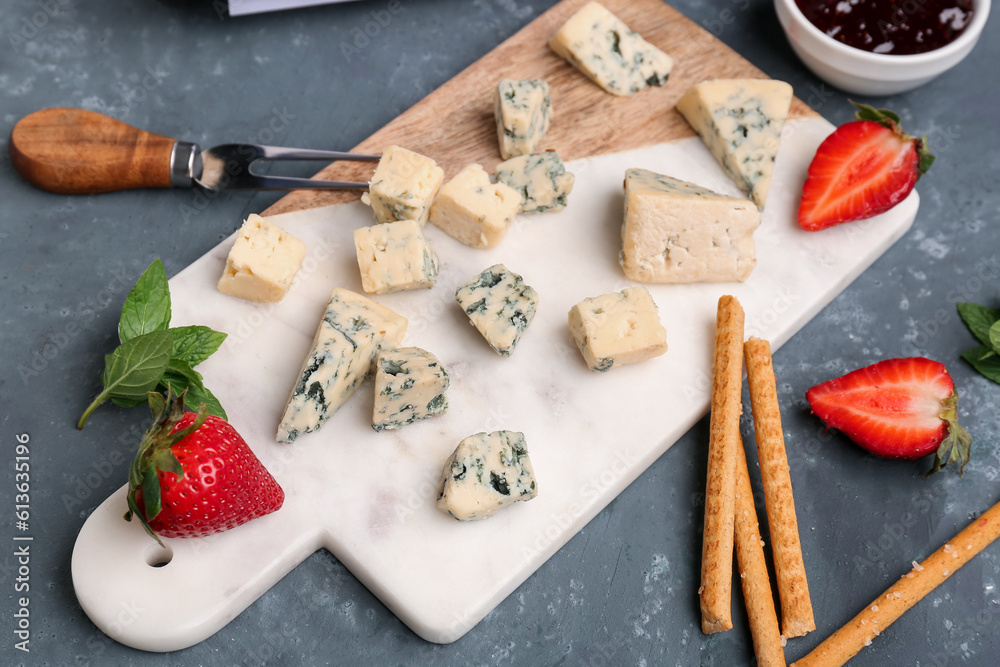 Board with pieces of tasty cheese on grey background