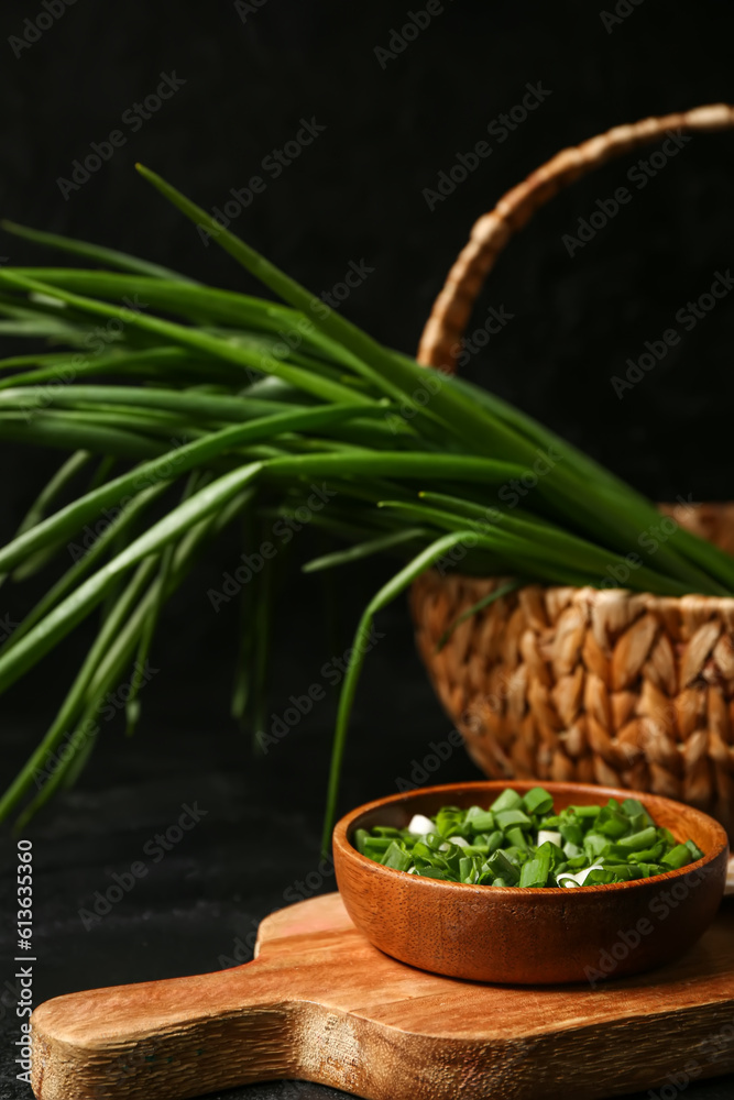 Bowl with fresh cut green onion on dark background