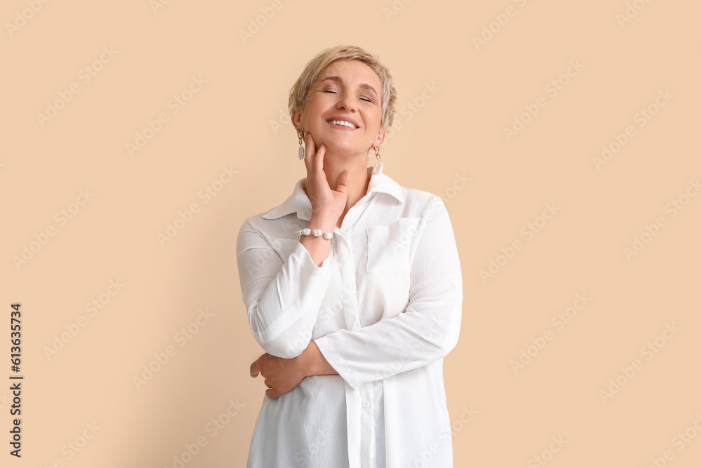 Mature blonde woman in white shirt on beige background