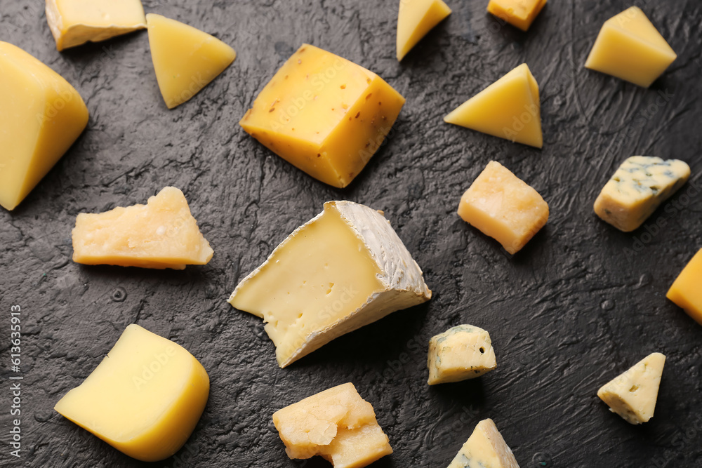 Pieces of tasty cheese on dark background