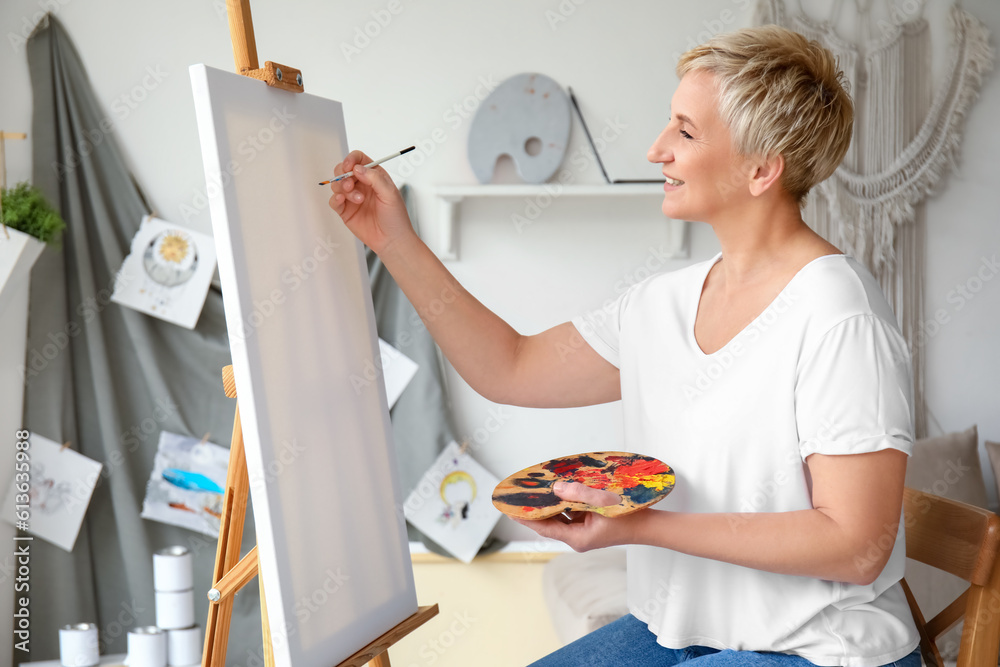 Mature female artist painting picture in  workshop